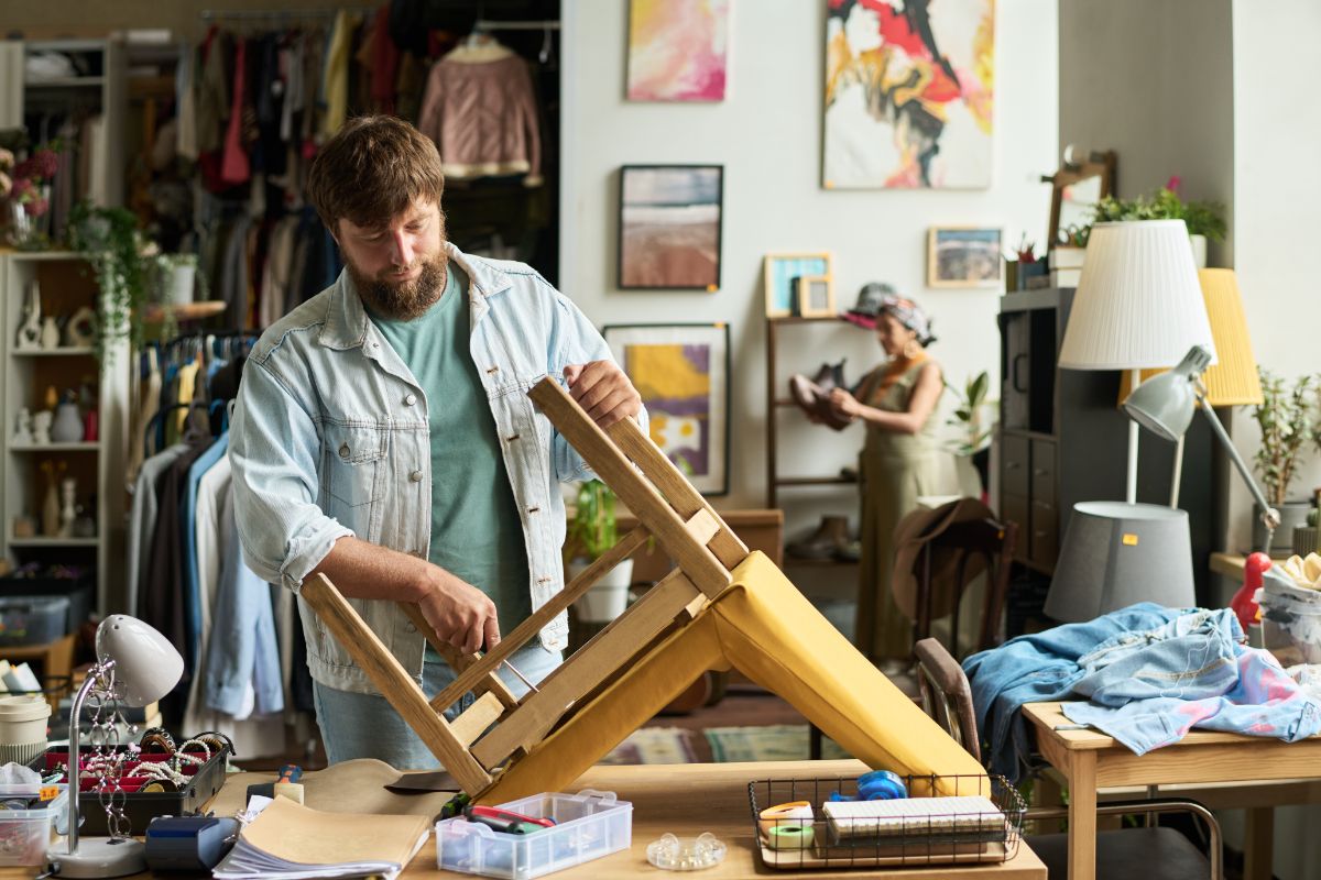 Muž upravuje starú čalúnenú stoličku.