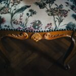 Detail na starožitností čalúnený taburet.