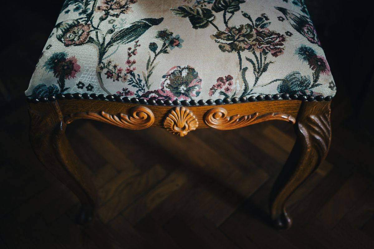 Detail na starožitností čalúnený taburet.