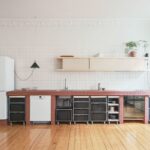 Kuchyňa s lineárnou linkou s tehlovým obkladom pracovnej dosky, policou s posuvnými dvierkami a prepravkami na kolieskach.