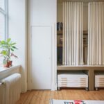 Časť interiéru s policami ukrytými za jemným bielym závesom.