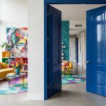 Miestnosť s lesklými modrými dverami, farebným zariadením v pozadí.