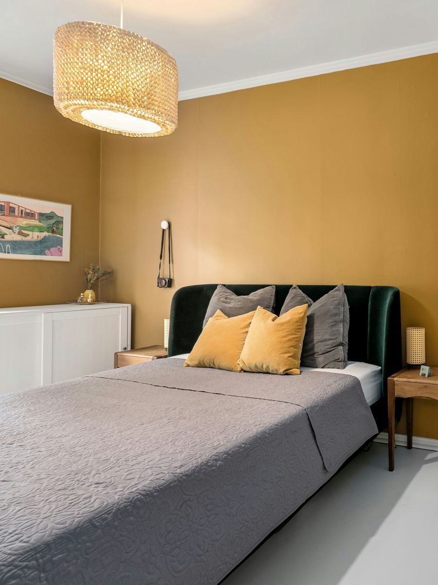 Posteľ s čiernym čelom a stenou so saténovou povrchovou úpravou.