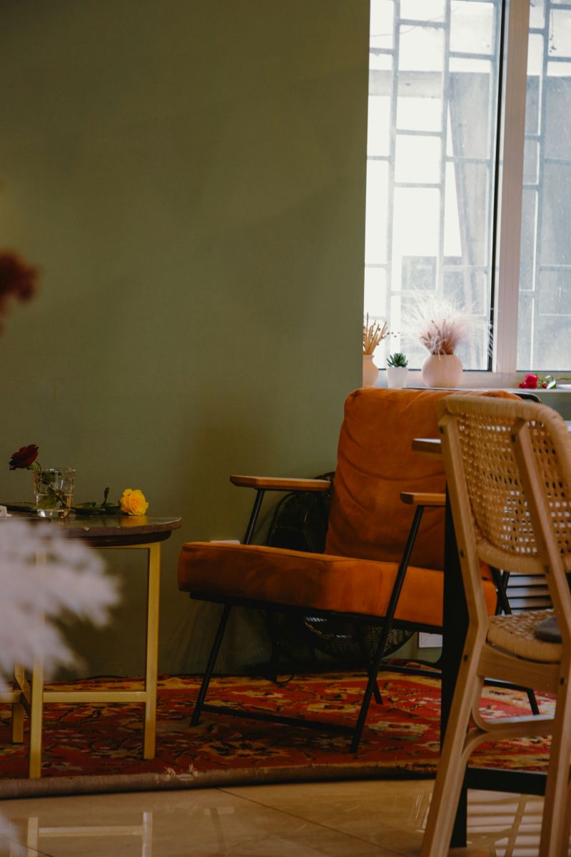 oranžové kreslo pri olivovozelenej stene s jemným odleskom.