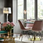 Smaragdovozelená sedačka, staroružové zamatové stoličky, zlatý kovový stolík a dizajnová sklenená stojaca lampa.