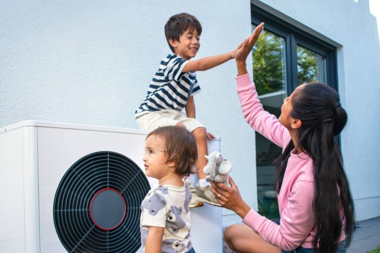 Mladá žena si tľapla s chlapcom sediacom na vonkajšej jednotke tepelného čerpadla Protherm GeniaAir.