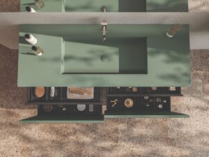 Pohľad zhora na zelenú skrinku z kolekcie Amiata Karol s vysunutými zásuvkami a zapusteným umývadlom.