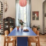 Jedáleň s modrým laminátovým jedálenským stolom, drevenými ohýbanými stoličkami, pruhovaným svietidlom a svetlou drevenou podlahou.