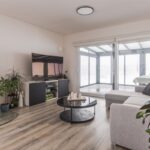 vetlá obývacia izba so sivou rohovou sedačkou, čiernymi krbovými kachľami a veľkým oknom.