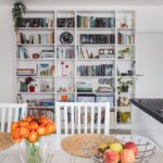 Vysoká biela knižnica plná kníh, rastlín a dekorácií.