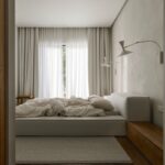 Svetlá spálňa s nízkou čalúnenou posteľou, ľanovou posteľnou bielizňou a minimalistickými bielymi nástennými lampami.