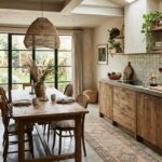 Rustikálna kuchyňa s drevenou linkou, masívnym jedálenským stolom, betónovým drezom a prúteným lustrom v štýle wabi sabi.