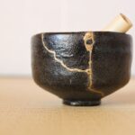 mavá keramická miska s viditeľnými zlatými spojmi kintsugi.