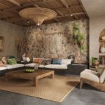 Obývacia izba s kamenným obkladom steny, dreveným trámovým stropom a nízkou sedačkou s farebnými vankúšmi v štýle wabi-sabi.