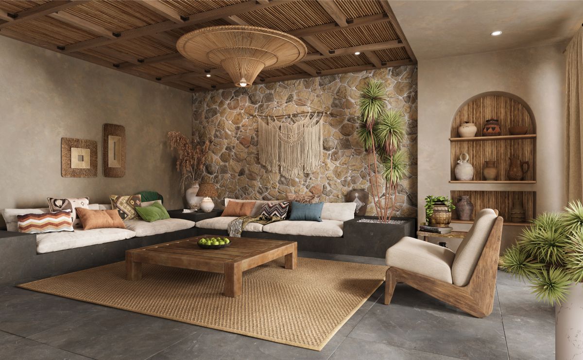 Obývacia izba s kamenným obkladom steny, dreveným trámovým stropom a nízkou sedačkou s farebnými vankúšmi v štýle wabi-sabi.