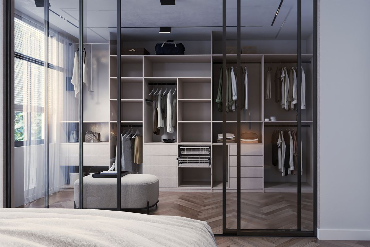Moderná spálňa s bielou posteľou a šatníkovou skriňou s presklenými dverami a drevenými policami, v ktorej sú zavesené šaty a bundy.
