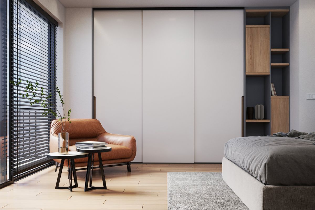 Moderná obývacia izba s béžovým kreslom, stolíkmi, rastlinami a bielou šatníkovou skriňou s posuvnými dverami a drevenými policami.