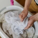 Detail namáčania bielizne v plastovej nádobe pred praním.