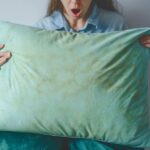 Prekvapená žena drží zelený vankúš so žltými škvrnami.