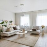 Obývacia izba so svetlou rohovou sedačkou, bielym oválnym stolíkom a vysokou rastlinou.