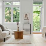 Obývacia izba s bielou klasickou pohovkou, okrúhlym dreveným stolom a čiernym kovovým jedálenským setom.