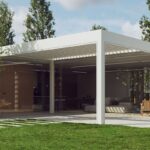 Pergola v bielej farbe pred veľkoformátovým presklením bungalovu, ktoré prepája dennú zónu s terasou.