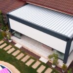 Pergola, zastrešujúca terasu, s roletami proti slnku.