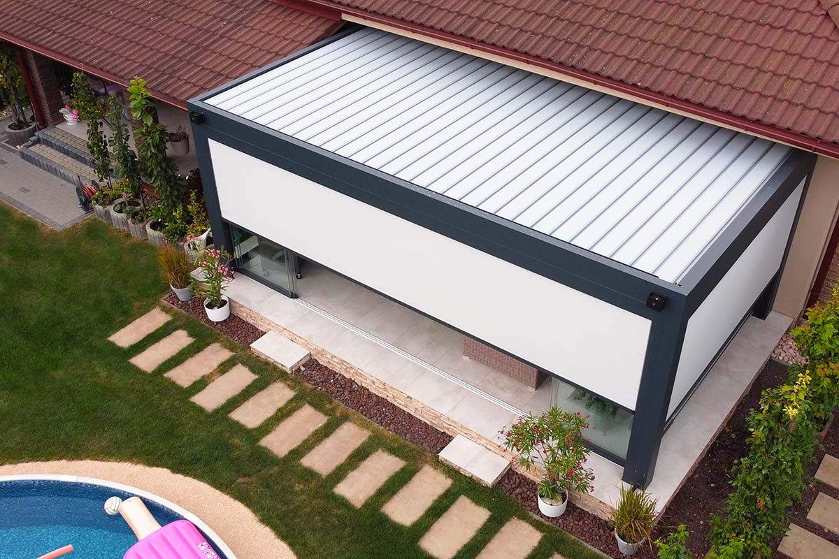 Pergola, zastrešujúca terasu, s roletami proti slnku.