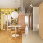 Otvorený interiér s výraznou žltou knižnicou, liatou aj parketovou podlahou, tehlovou stenou a priznaným betónovým prekladom.