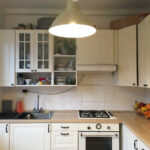 Pôvodná kuchyňa s bielou rustikálnou linkou, keramickým obkladom a laminátovou pracovnou doskou.