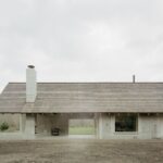 Dom s dreveným obkladom a vysokou sedlovou strechou a veľkým preskleným oknom.