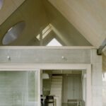 Interiér spálne s dreveným obkladom na stenách a strope a veľkým oknom s výhľadom do záhrady.