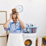 Žena v rovnošate sa drží za hlavu pri naloženej práčke.
