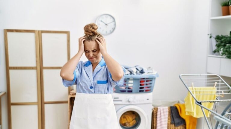 Žena v rovnošate sa drží za hlavu pri naloženej práčke.