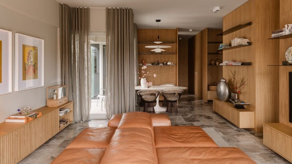 Obývacia izba s hnedou koženou sedačkou, mramorovou podlahou a jedálenským kútom v pozadí.