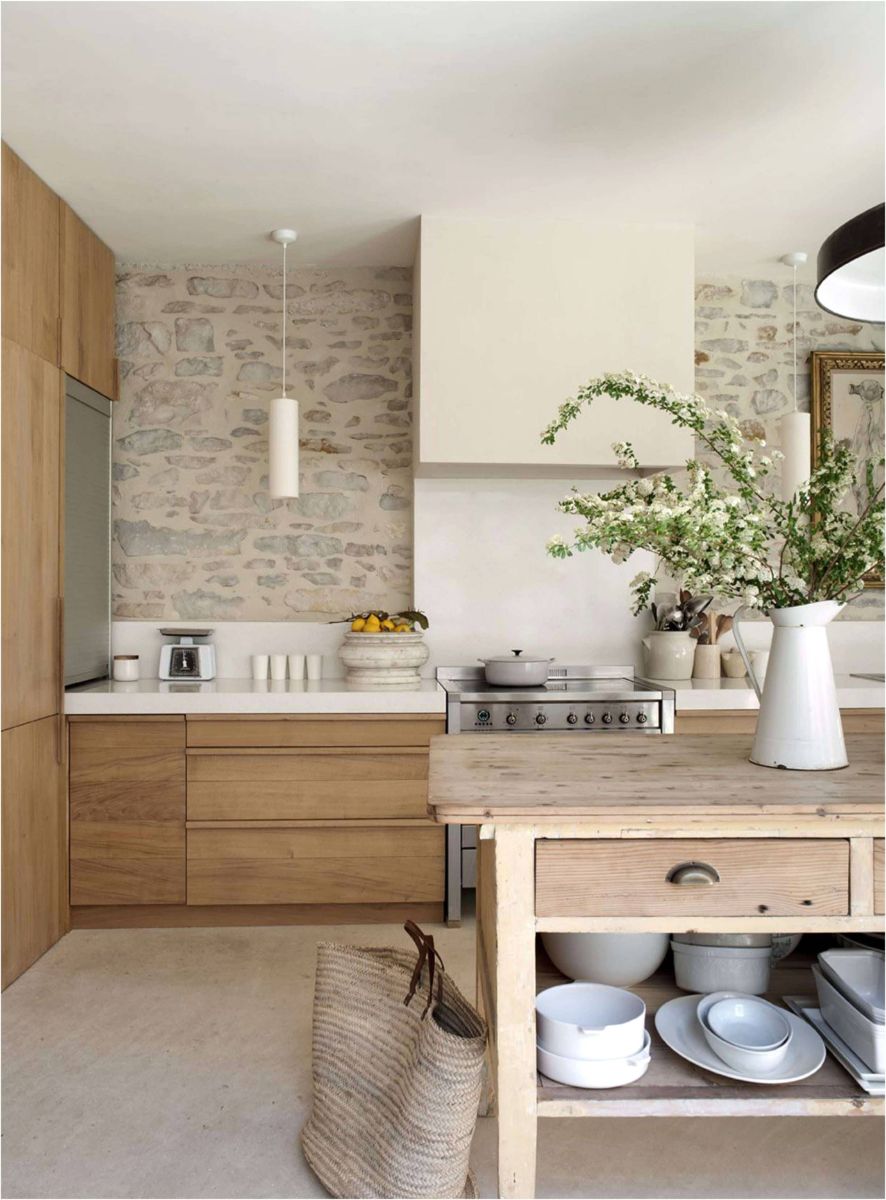 Kuchyňa s kamenným obkladom steny, svetlou drevenou linkou a rustikálnym ostrovom s bielou keramikou.