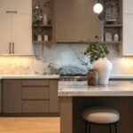 Moderná kuchyňa s drevenými a bielymi skrinkami a mramorovou zástenou i pracovnou doskou.