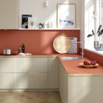 Moderná kuchyňa s terakotovým pracovným pultom, béžovými skrinkami a dubovými parketami.