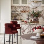 Luxusná kuchyňa s mramorovým ostrovom, vínovými zamatovými stoličkami a sklenenými glóbusovými svietidlami.