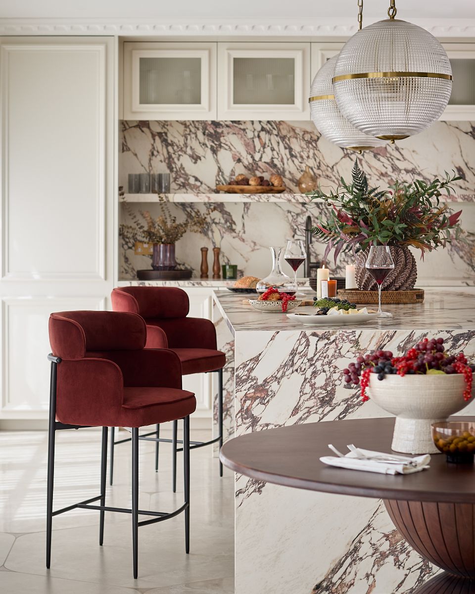 Luxusná kuchyňa s mramorovým ostrovom, vínovými zamatovými stoličkami a sklenenými glóbusovými svietidlami.