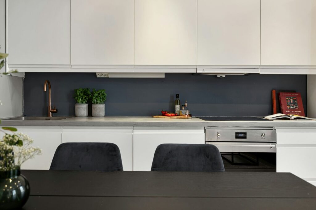 Moderná kuchyňa s bielymi skrinkami s čistými líniami a integrovaným digestorom.