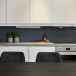 Moderná kuchyňa s bielymi skrinkami s čistými líniami a integrovaným digestorom.