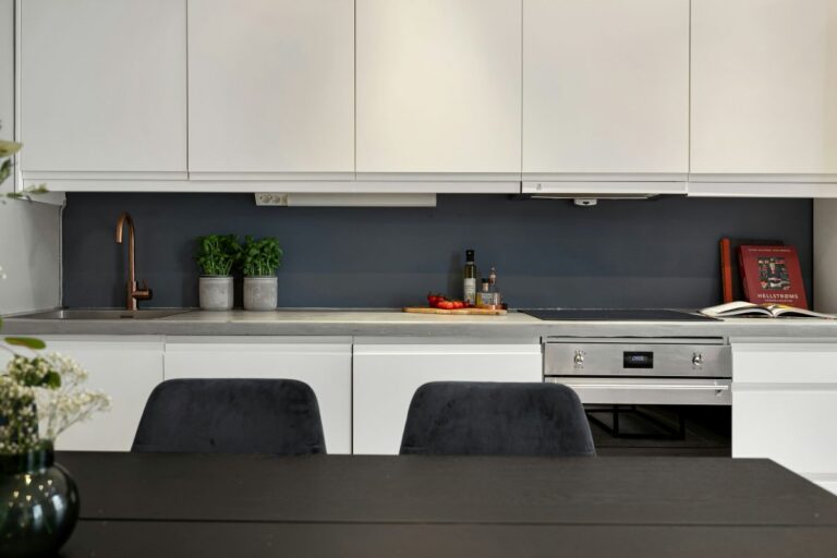 Moderná kuchyňa s bielymi skrinkami s čistými líniami a integrovaným digestorom.