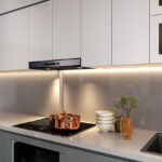 Moderná kuchyňa s bielymi skrinkami s čistými líniami, podsvietenou pracovnou doskou a integrovaným digestorom.