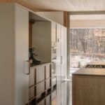 Kuchyňa s vysokými svetlými skriňami, dreveným ostrovom a zapustenou antikorovou rúrou.