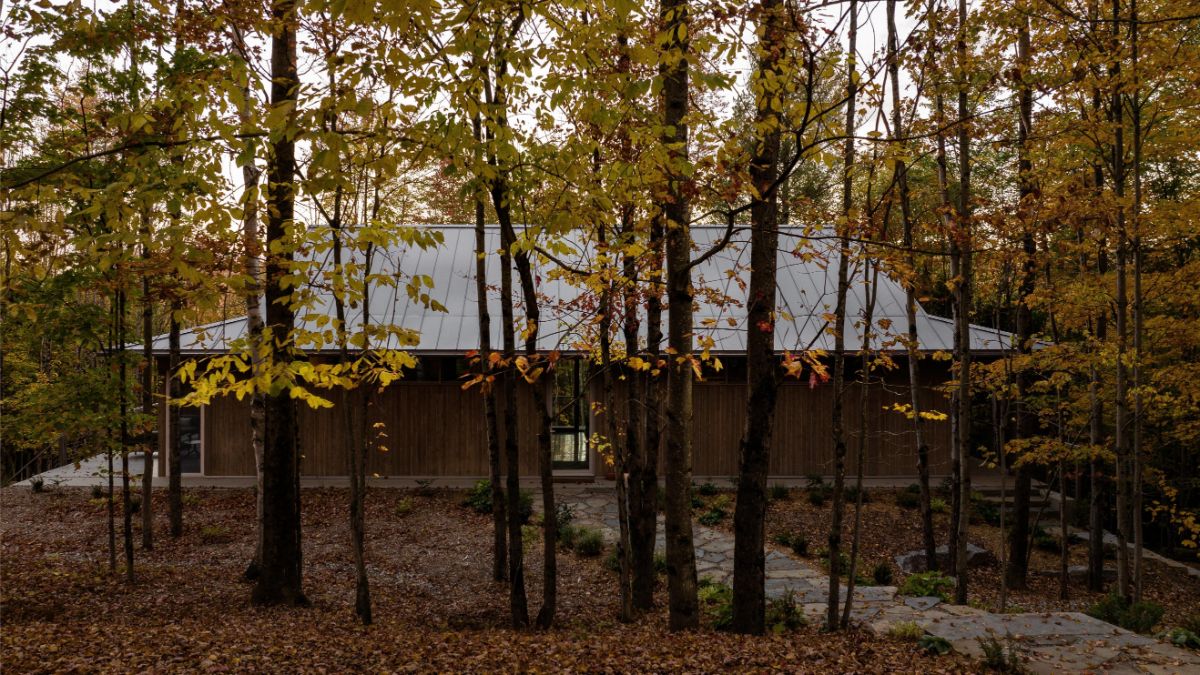 Chata v lese s plechovou strechou a drevenou fasádou.