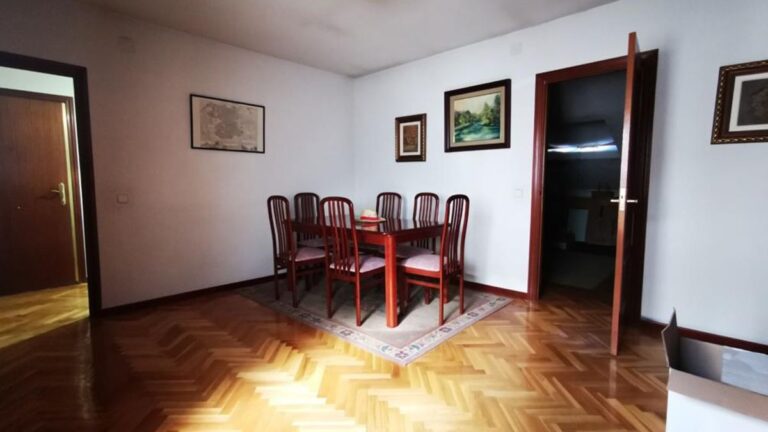 Jedáleň s masívnym dreveným stolom so stoličkami, klasickými obrazmi na stenách a parketovou podlahou.