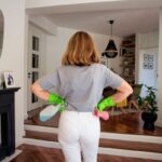 Žena stojaca chrbtom v priestore s čistiacimi prostriedkami v ruke.