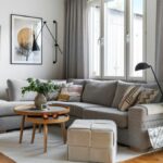 Sivá rohová pohovka, okrúhly drevený konferenčný stolík a jemný svetlý koberec v obývacej izbe.