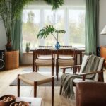 Obývacia izba s dreveným príborníkom, pleteným kreslom, zelenými závesmi a veľkou palmou v hnedom kvetináči.